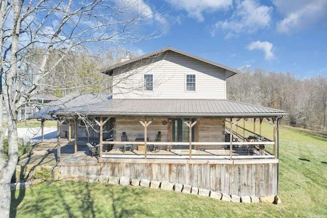 back of property featuring a yard, a chimney, and metal roof