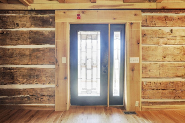 entrance foyer with visible vents, wood-type flooring, and wooden walls