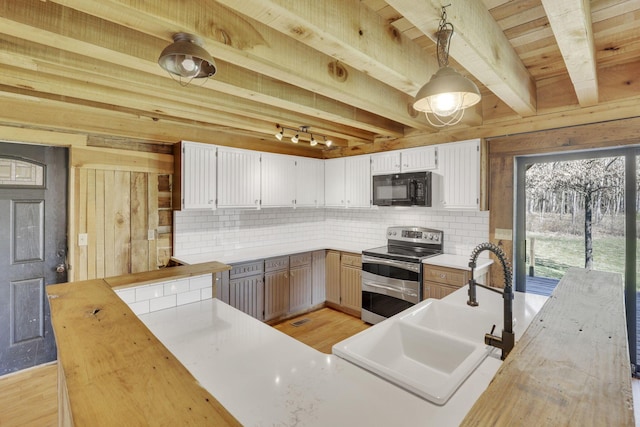 kitchen with range with two ovens, a sink, black microwave, beamed ceiling, and tasteful backsplash