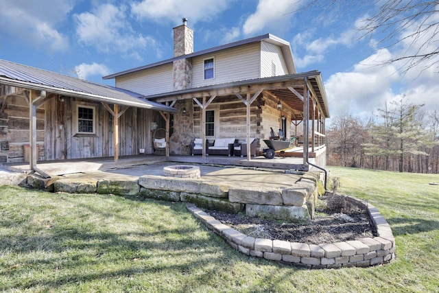 rear view of house with an outdoor living space with a fire pit, a chimney, metal roof, a yard, and a patio