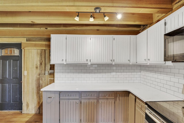 kitchen featuring decorative backsplash, stainless steel range with electric stovetop, light countertops, and black microwave