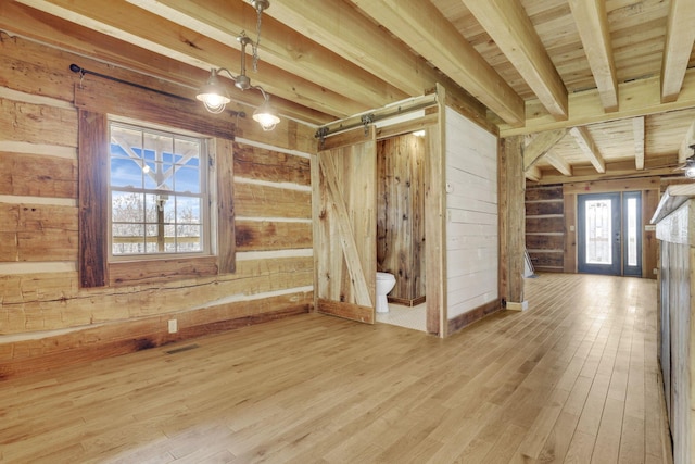 unfurnished room with beamed ceiling, visible vents, wood finished floors, french doors, and wood walls