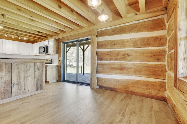 interior space with light wood-type flooring, wooden walls, and track lighting