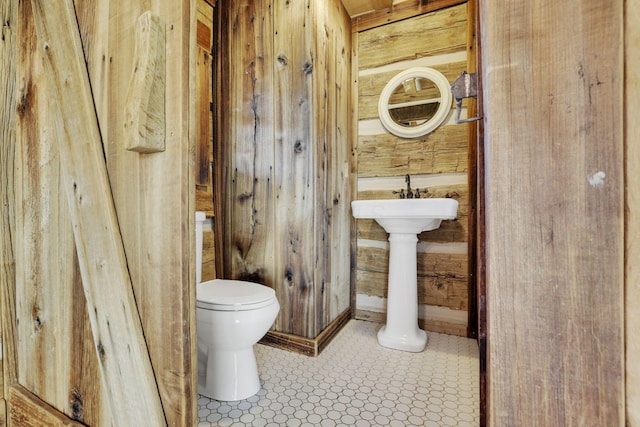 half bath with wooden walls and toilet