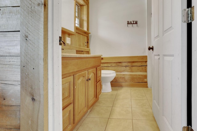 half bath featuring tile patterned flooring, toilet, and vanity