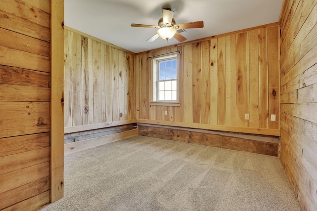 carpeted empty room featuring wooden walls and ceiling fan