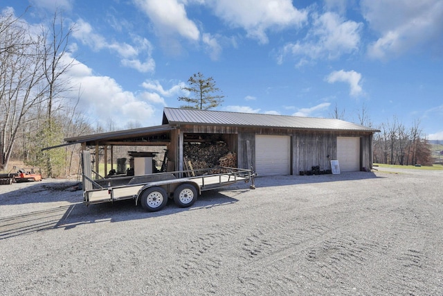 exterior space with a garage, driveway, metal roof, and an outdoor structure