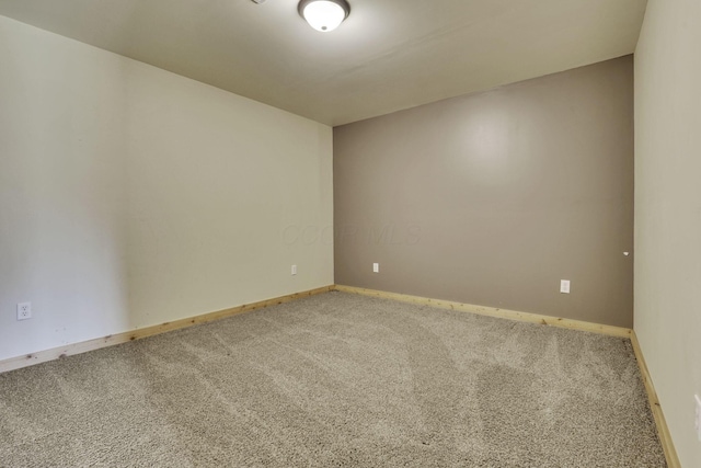 empty room featuring baseboards and carpet flooring