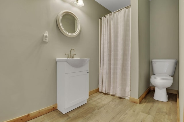 full bathroom featuring toilet, vanity, baseboards, and wood finished floors