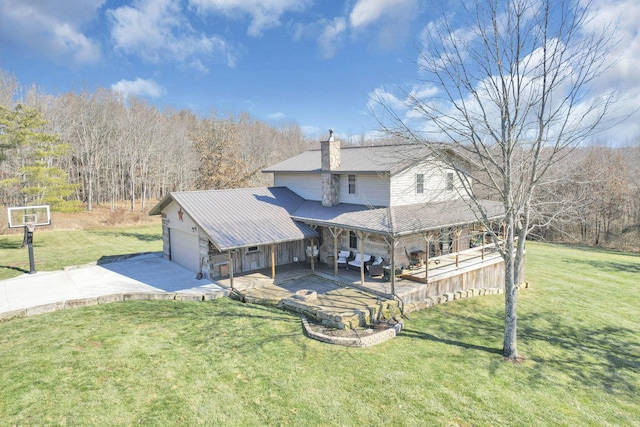 back of house featuring concrete driveway, a yard, an attached garage, and a chimney