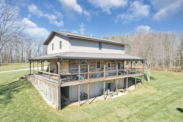 back of house featuring a yard, stone siding, and metal roof