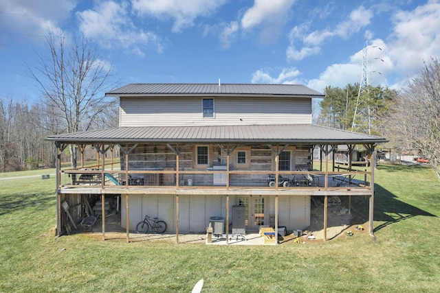 rear view of property with a deck, a yard, and metal roof