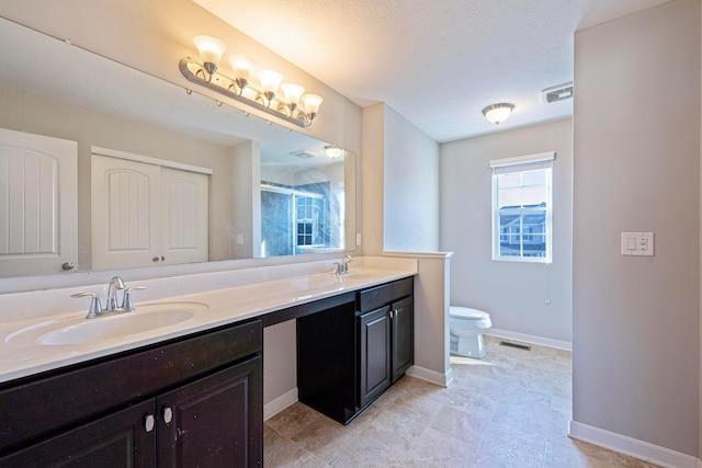 bathroom featuring double vanity, toilet, baseboards, and a sink