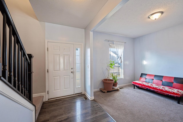 foyer entrance with baseboards, a textured ceiling, wood finished floors, and stairs