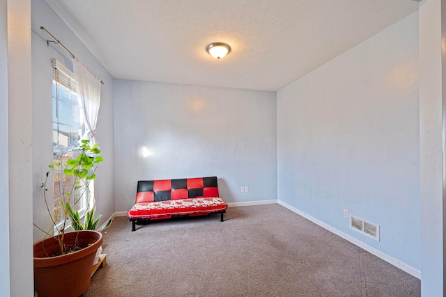 living area featuring visible vents, baseboards, carpet, and a textured ceiling