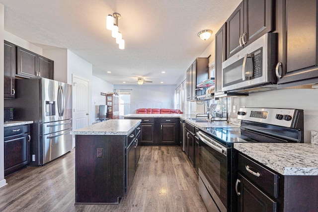 kitchen featuring appliances with stainless steel finishes, a center island, light countertops, and wood finished floors