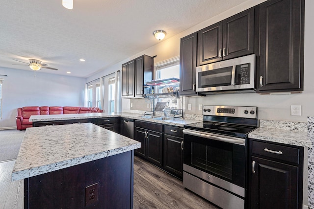 kitchen with ceiling fan, light countertops, open floor plan, and stainless steel appliances