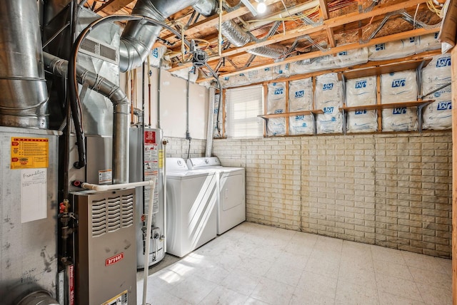 laundry room with tile patterned floors, gas water heater, brick wall, and washing machine and clothes dryer