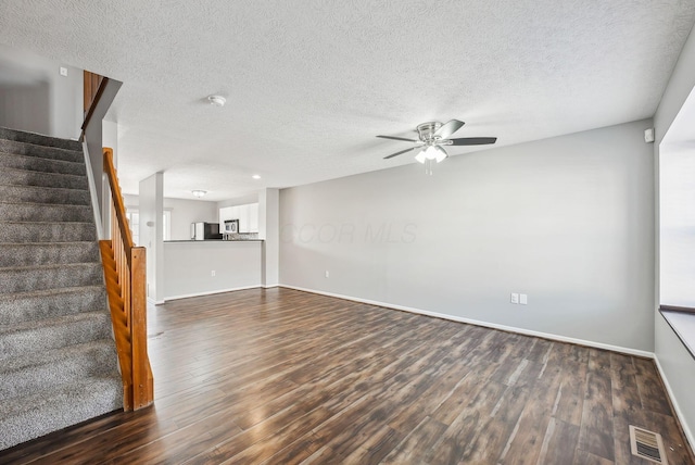 unfurnished living room featuring visible vents, a ceiling fan, dark wood finished floors, stairway, and baseboards