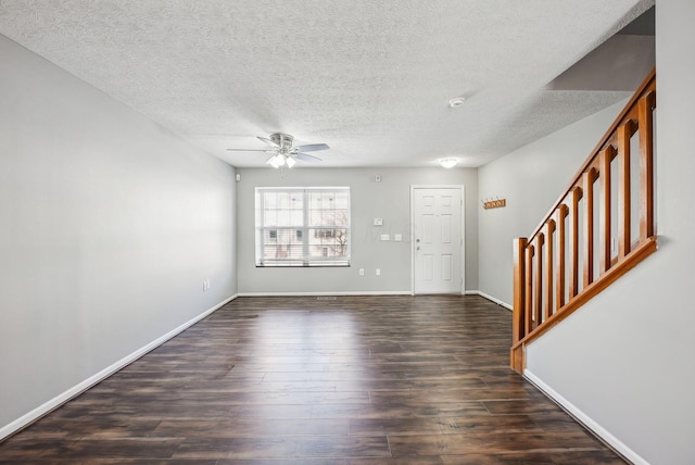 foyer entrance featuring a ceiling fan, baseboards, stairs, dark wood-type flooring, and a textured ceiling