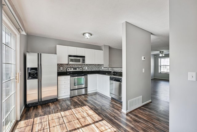 kitchen with visible vents, backsplash, dark wood-style floors, white cabinets, and stainless steel appliances