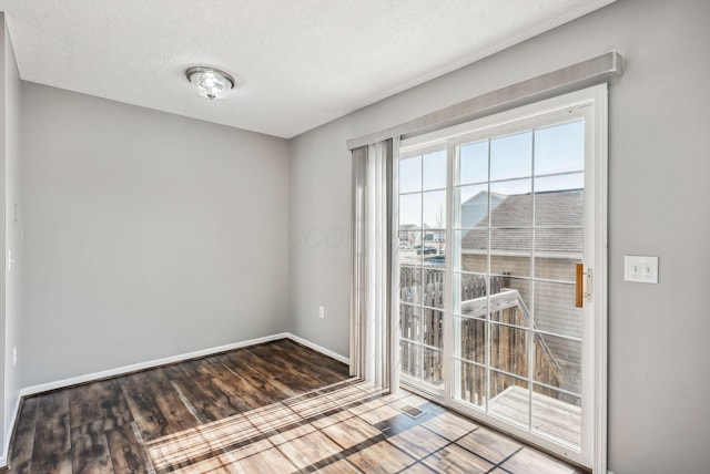 doorway with a textured ceiling, baseboards, and wood finished floors