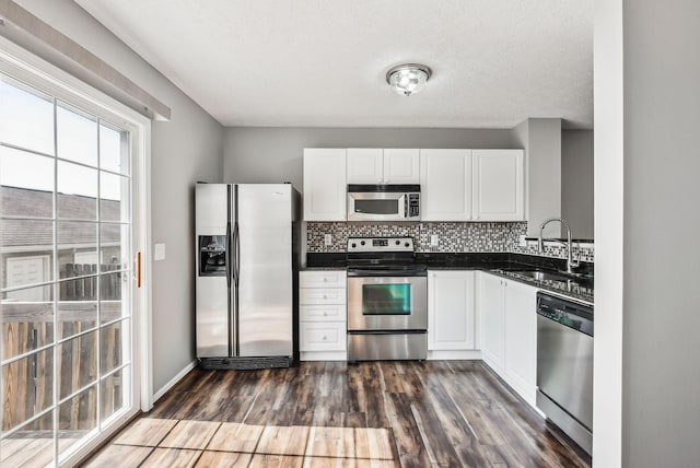 kitchen featuring a sink, dark wood-type flooring, appliances with stainless steel finishes, dark countertops, and tasteful backsplash