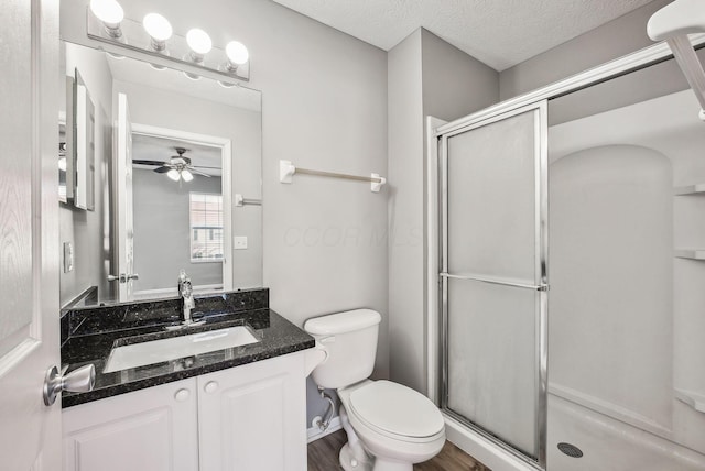 bathroom featuring toilet, a stall shower, a ceiling fan, a textured ceiling, and vanity