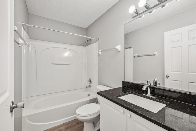 full bath with vanity, a textured ceiling, wood finished floors, shower / washtub combination, and toilet