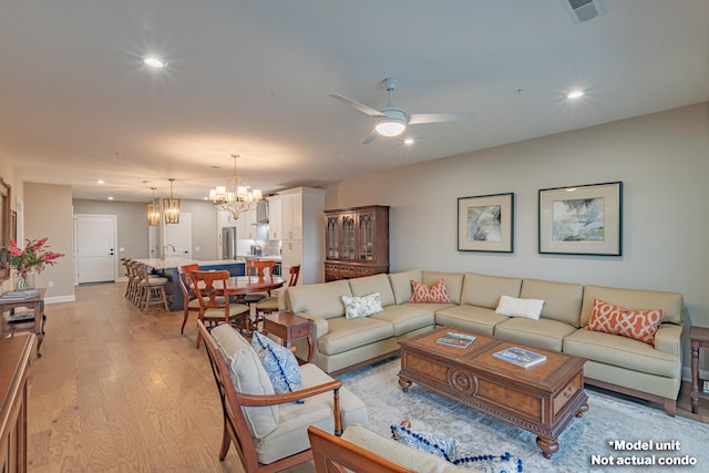 living area featuring light wood-type flooring, visible vents, recessed lighting, and ceiling fan with notable chandelier