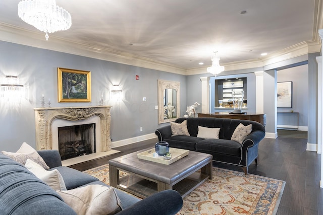 living room with ornamental molding, wood finished floors, a high end fireplace, an inviting chandelier, and baseboards