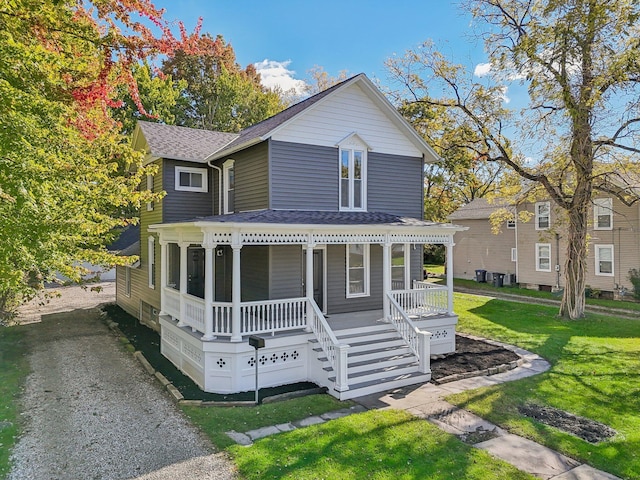 view of front of property with roof with shingles, covered porch, and a front lawn