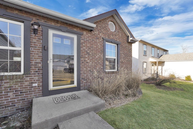 property entrance featuring brick siding and a yard