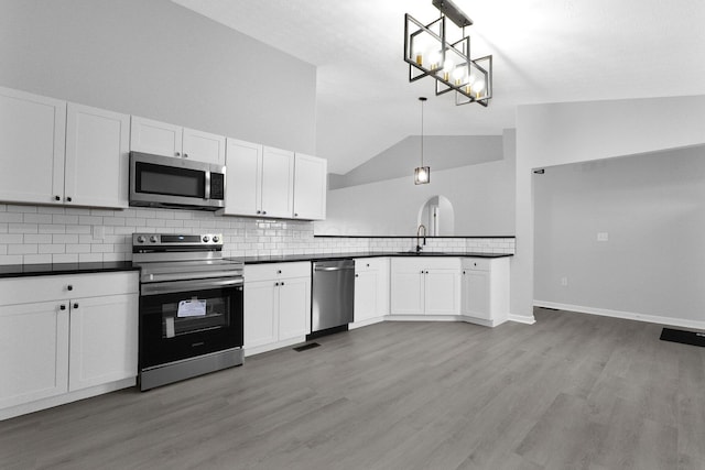 kitchen with a sink, stainless steel appliances, dark countertops, and white cabinetry