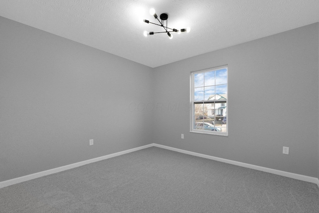 unfurnished room with baseboards, a textured ceiling, an inviting chandelier, and carpet flooring