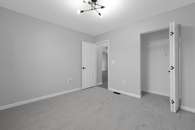 unfurnished bedroom with an inviting chandelier, baseboards, a closet, and a textured ceiling