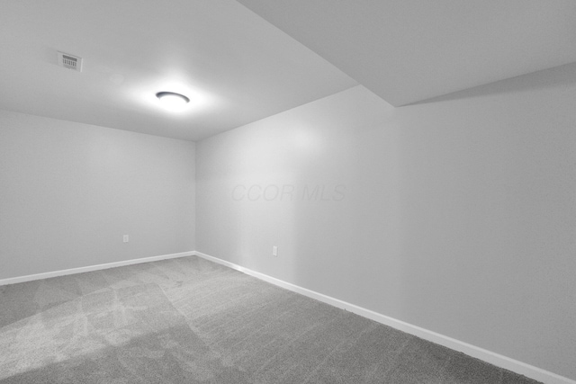 carpeted spare room with visible vents and baseboards