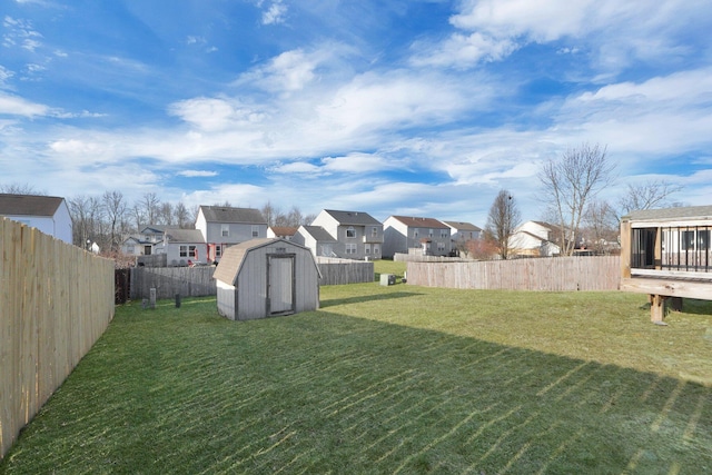 view of yard featuring a storage unit, a residential view, an outbuilding, and a fenced backyard