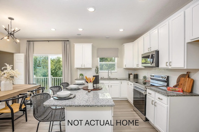 kitchen featuring a sink, appliances with stainless steel finishes, a breakfast bar area, white cabinets, and decorative backsplash