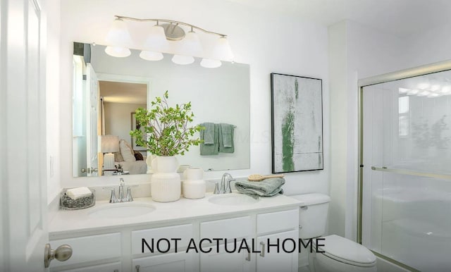 ensuite bathroom featuring a sink, toilet, a stall shower, and double vanity