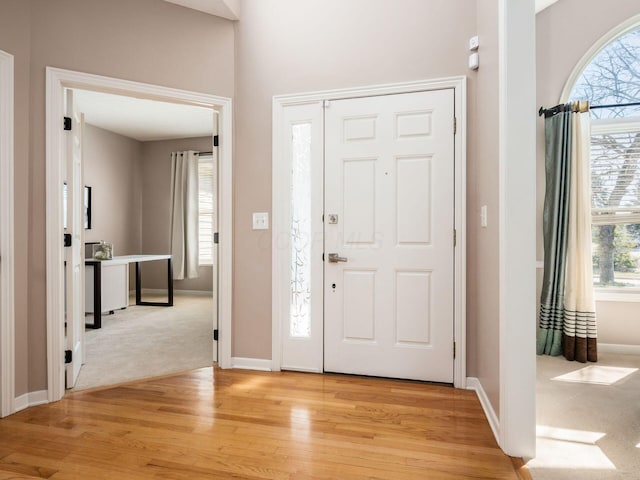 foyer entrance with baseboards and light wood-style flooring