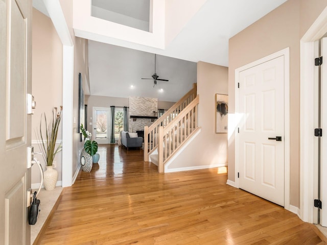 foyer featuring lofted ceiling, a ceiling fan, light wood-style floors, baseboards, and stairs