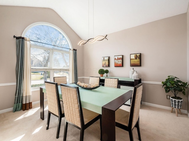 dining space with vaulted ceiling, baseboards, and light carpet