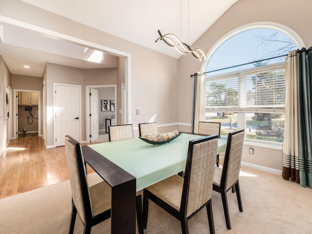 dining room with baseboards, light carpet, and lofted ceiling