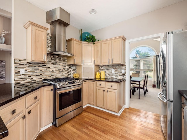 kitchen featuring backsplash, light brown cabinets, light wood-type flooring, stainless steel appliances, and wall chimney exhaust hood