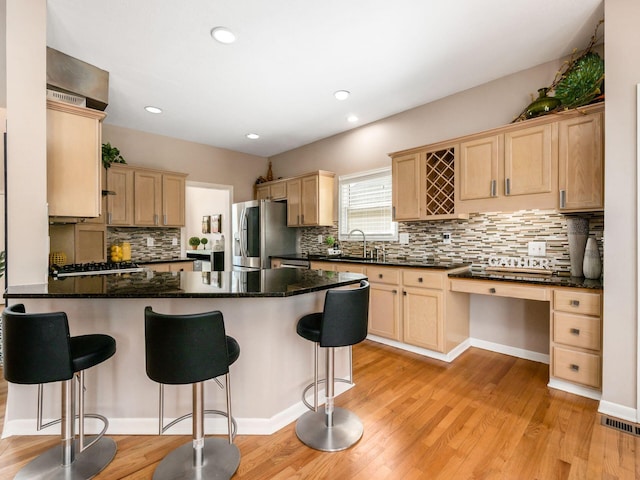 kitchen featuring a peninsula, light wood-style floors, stainless steel refrigerator with ice dispenser, and light brown cabinetry