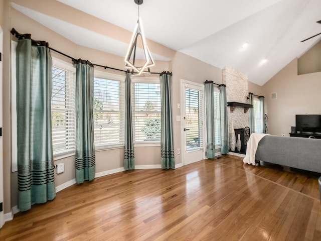 dining area featuring baseboards, lofted ceiling, a fireplace, and light wood finished floors