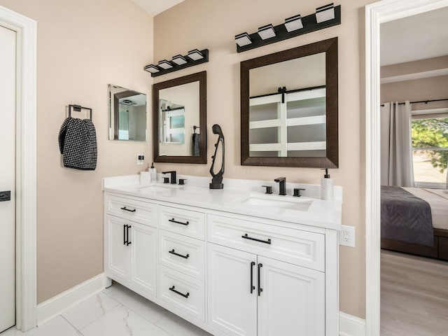 full bathroom with a sink, baseboards, marble finish floor, and double vanity