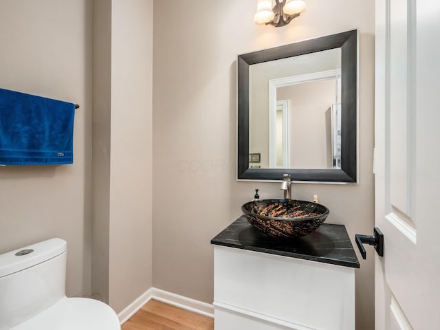 bathroom featuring vanity, toilet, wood finished floors, and baseboards