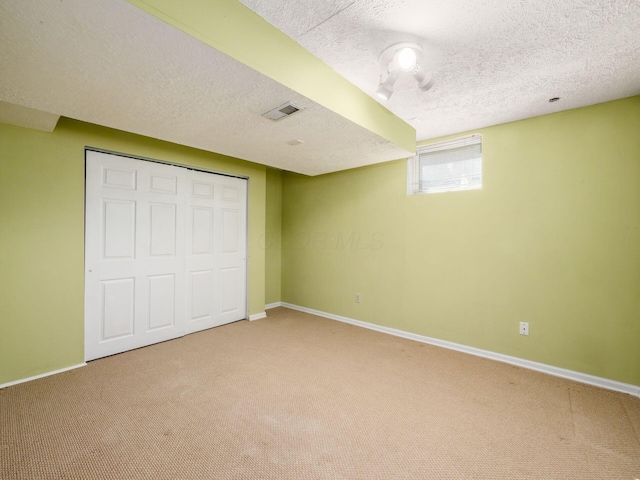 unfurnished bedroom with a textured ceiling, carpet, visible vents, and baseboards